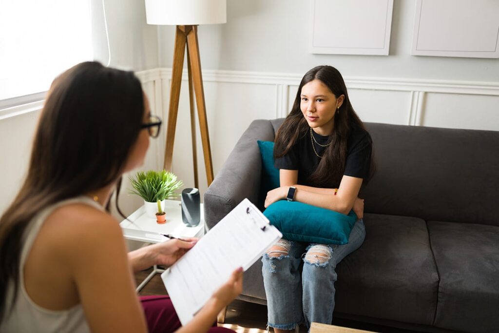 a teen talks to a therapist during an adolescent day treatment program