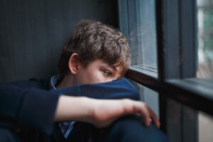 Teen leans against window and thinks about his unresolved trauma and addiction