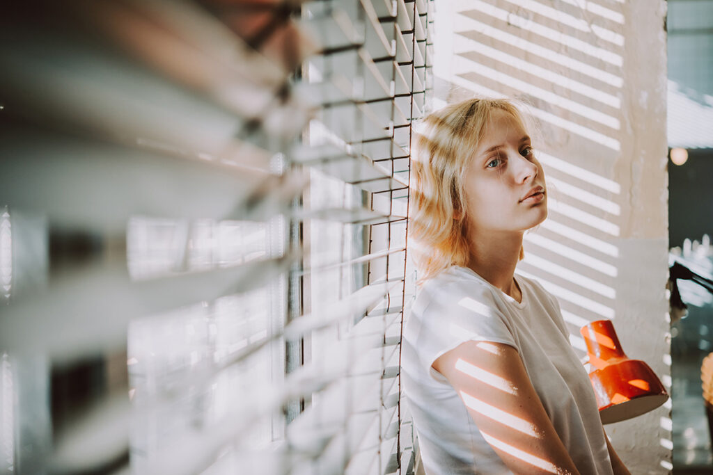 Woman leans on a window while considering the best medication for OCD treatment in teens